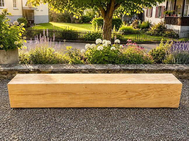Holzbank auf Kiesplatz vor Blumenbeet