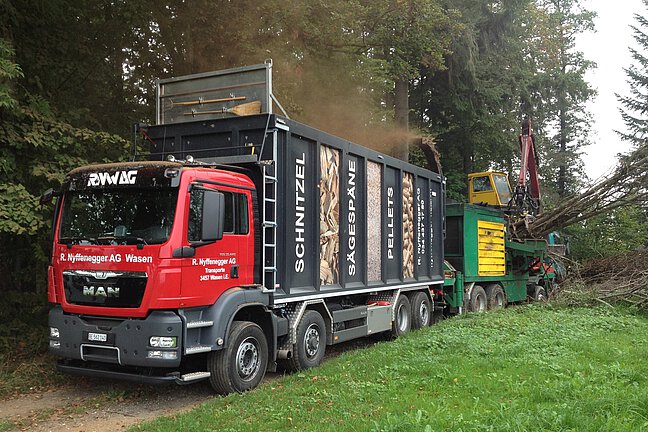 Herstellung von Holzschnitzel im Wald mit Hacker und Lastwagen