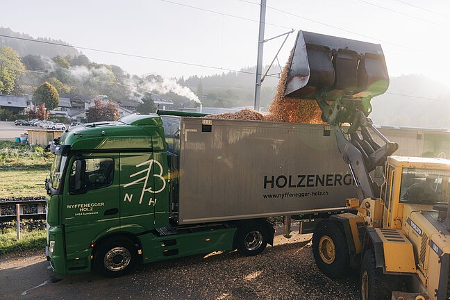 Lastwagen wird mit einem Pneulader mit Holzschnitzel beladen
